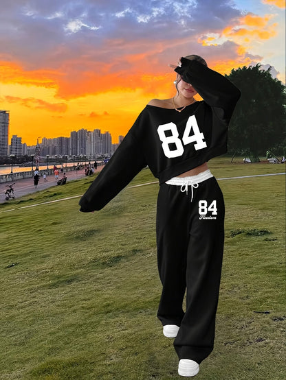 Tweedelige damesjoggingpak met crop top en wijde broek, grijs-zwart, print met nummer "84"